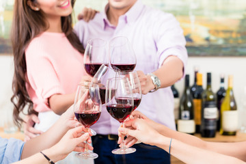 Couple toasting red wineglasses with friends