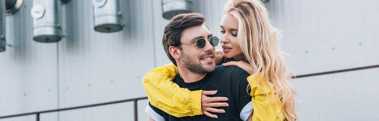 panoramic shot of attractive and blonde woman and handsome man hugging on roof