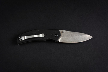 Folding pocket knife isolated on a black background.