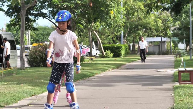 Asian girl playing roller bladeing together in the park outdoor .