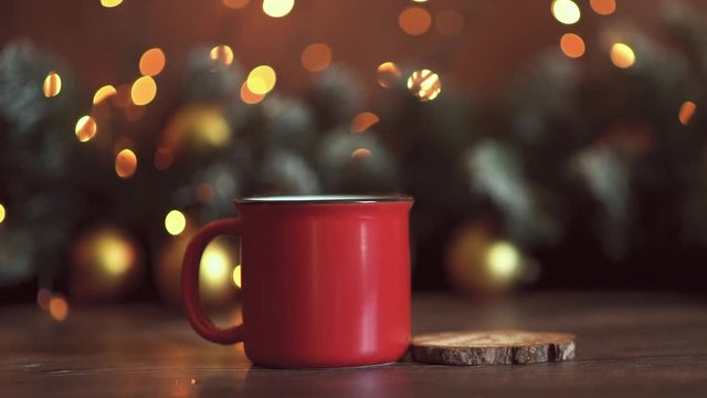 Slow motion marshmallow in a mug with a hot drink sprinkle cinnamon near candy cane Christmas beads and mittens.