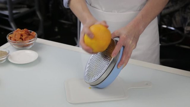 confectioner cuts the orange peel, citrus zester grating peeling orange peel