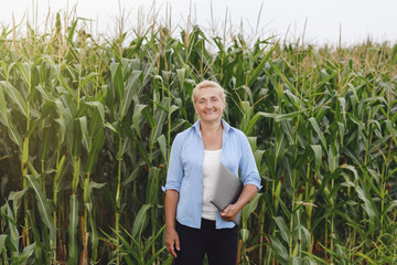 Female farmer in the field checking corn plants during a sunny summer day