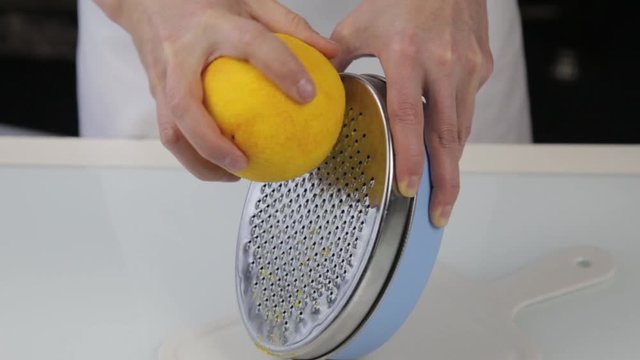 confectioner cuts the orange peel, citrus zester grating peeling orange peel