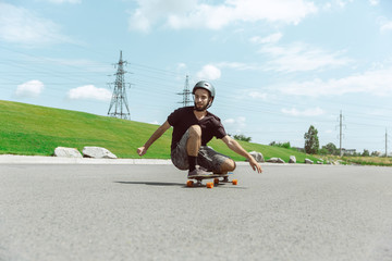 Skateboarder doing a trick at the city's street in sunny day. Young man in equipment riding and...