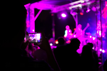The viewer shoots a rock concert on a smartphone. Bright scene with lights. The focus is blurred