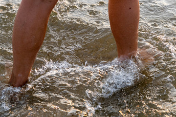 Human legs walking in sea water.