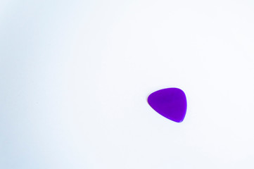 Perspective shoot of purple colored guitar pick under white surface