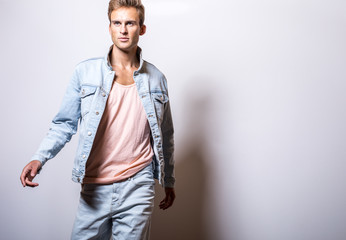 Handsome young man in jeans jacket pose in studio.