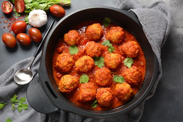 Meatballs in sweet and sour tomato sauce with spices served in a frying pan on dark background . Top view 