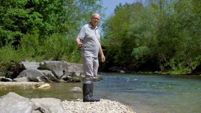 Retired Man Throwing Angler of Fishing Rod into River 
