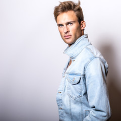 Handsome young man in jeans jacket pose in studio.