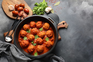 Meatballs in sweet and sour tomato sauce with spices served in a frying pan on dark background . Top view 