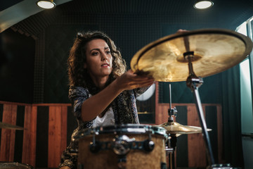 Woman playing drums during music band rehearsal