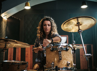 Woman playing drums during music band rehearsal