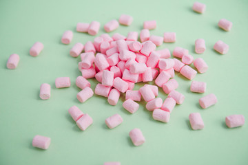 Obraz na płótnie Canvas handful of pink mini marshmallows on a green background