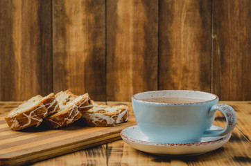 Breakfast with tea cup and pastries sliced on wooden board on a table. Selective focus