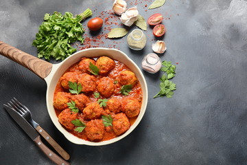Meatballs in sweet and sour tomato sauce with spices served in a frying pan on dark background . Top view