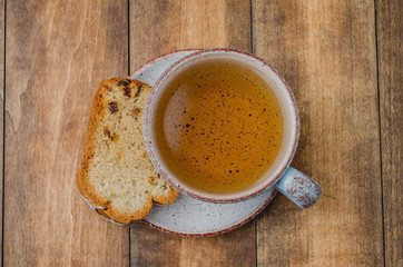 Tea cup and pastries piece on wooden table. Breakfast. Top view