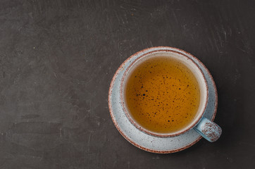 Blue cup of tea on dark stone background, top view and copyspace for text
