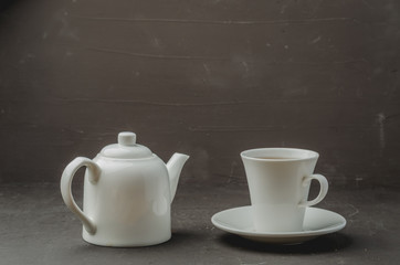 Tea cup and teapot on on dark stone table. Selective focus