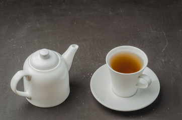 Tea cup and teapot on on dark stone background. Selective focus