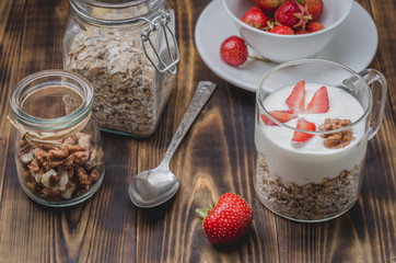 preparation of yogurt with a granule, nuts and strawberry on a wooden table. Selective focus