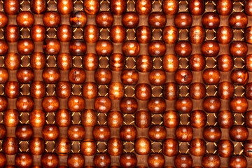 Wooden beads rug. Hand made car seat. Natural varnished wood background.