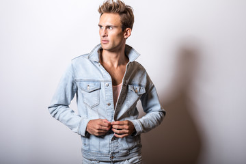 Handsome young man in jeans jacket pose in studio.