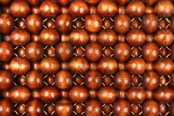 Wooden beads rug. Hand made car seat. Natural varnished wood background.