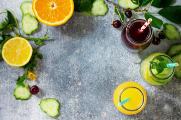 Various refreshments drinks - detox cucumber water, cherry juice and orange juice on stone table. Top view flat lay with copy space for your text.