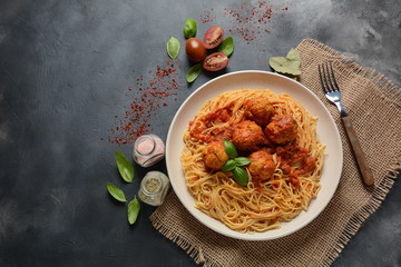 Pasta spaghetti with meatballs and tomato sauce on a white plate on a dark background
