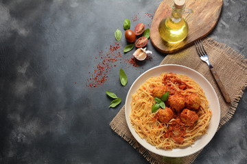 Pasta spaghetti with meatballs and tomato sauce on a white plate on a dark background