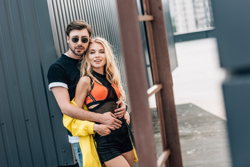 attractive woman and handsome man hugging and looking at camera