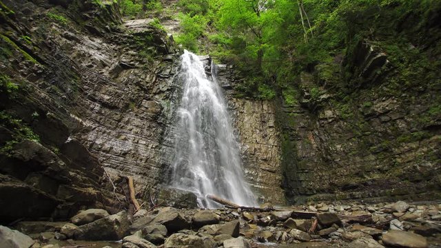 Waterfall Manyavsky Falls in an ancient flysch rocks with a lot of stone a and tree trunks   on the ground (4K, 25fps)