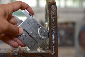 Technician's hand catch the Welding gauge to measuring the dimension of the welding.