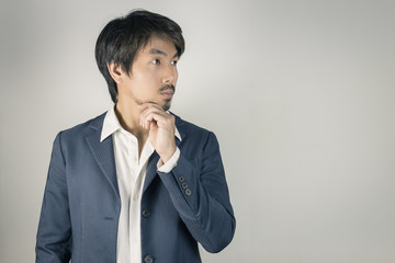 Portrait Man in Navy Blue Suit Looking Above and Touch Chin Pose Vintage Tone