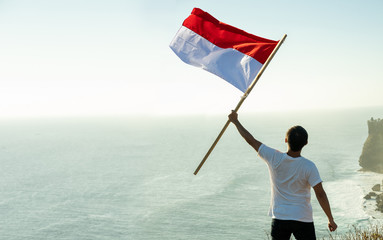 asian man with indonesian flag of indonesia on top of the mountain