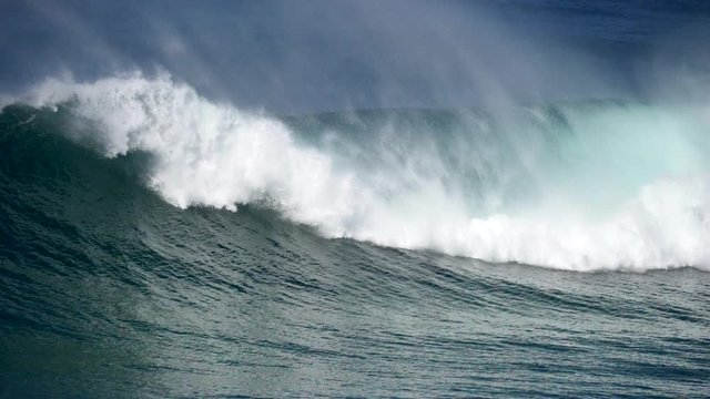 Mighty ocean wave rolling slowly and crashing against the coast, producing much splashes with white foam. Slow motion shot