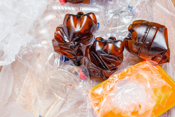 Lot of used plastic, crumpled empty bottles, packets, plastic orange dish, diaper, pollution recycle eco concept background close up selective focus