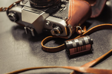 Vintage camera in a brown leather case lies on a dark table. Near the film. Selective focus. Macro....