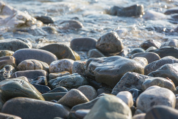 Ocean waves on black pebble stone coast