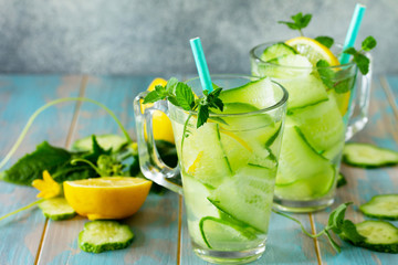 Glasses with fresh organic Cold and refreshing infused detox water with lemon and cucumber on wooden table. Copy space for your text.