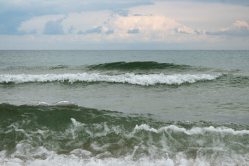 Sea waves, white foam crests, seashore, pink clouds at sunset