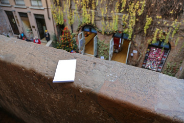 Paper notebook for romantic notes on the handhold of a stone balcony in the house of the legendary Shakespeare's Juliet. Verona, Italy