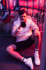 Fototapeta na wymiar handsome man sitting on floor and drinking champagne in night club