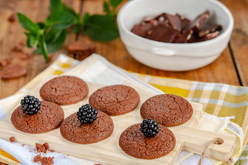 Chocolate cookies , mint, blackberries and crushed chocolate on a wooden table