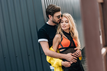 Naklejka premium attractive woman and handsome man in glasses hugging on roof