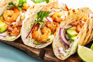 Shrimp tacos. Seafood fajitas with cabbage, onion, parsley in tortillas served on wooden cutting board - 281398280