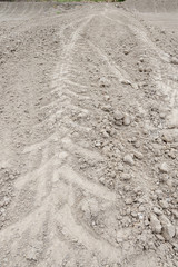 Close up Tire traces of large tractor wheels on dry ground, gray-brown